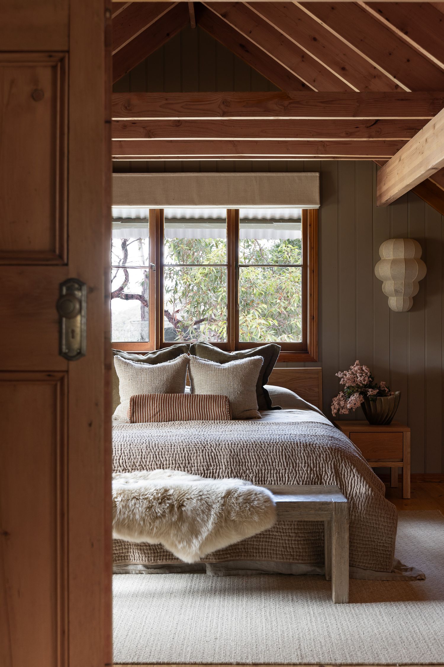 Editorial bedroom photography through timber doorway in a relaxed coastal home in Hyams Beach on the South Coast of NSW.