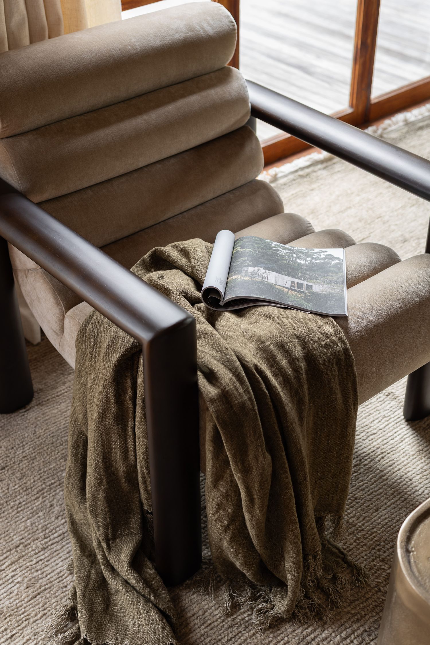 Detailed interior styling photography of sculptural armchair and layered textures in a coastal home in Hyams Beach NSW.