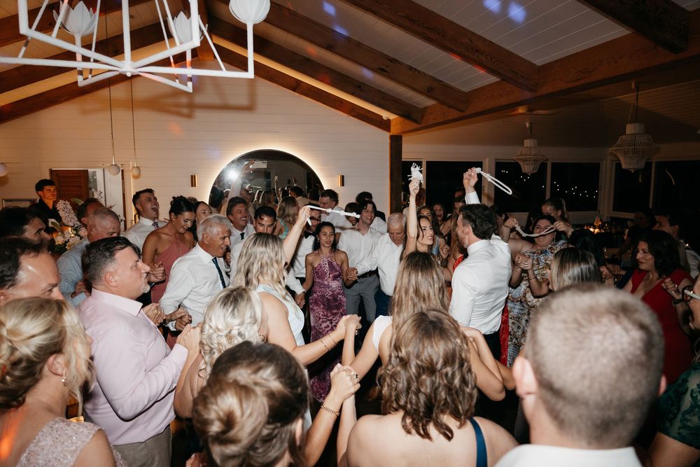Guests dancing and celebrating at a lively indoor wedding reception party.