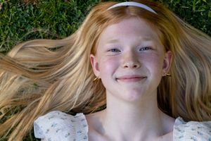 Smiling girl with freckles lying on green grass with her hair spread around her at eatonville park taken by pierce county photographer