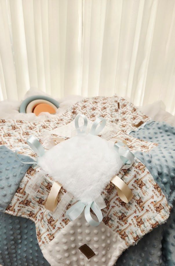 Soft baby blanket set with teddy bear print, white minky lovey with satin ribbons, and blue dimple dot blanket.