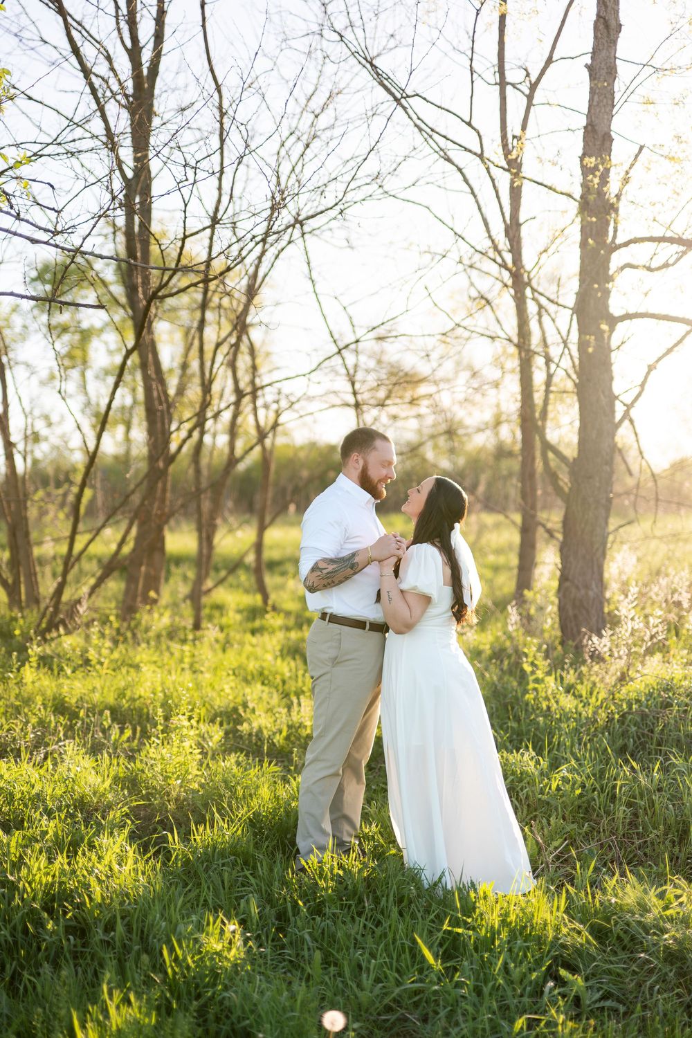 Couple sharing tender moment among trees in golden sunset light.