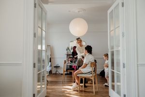 Bride getting hair and makeup done in bright white room with French doors.