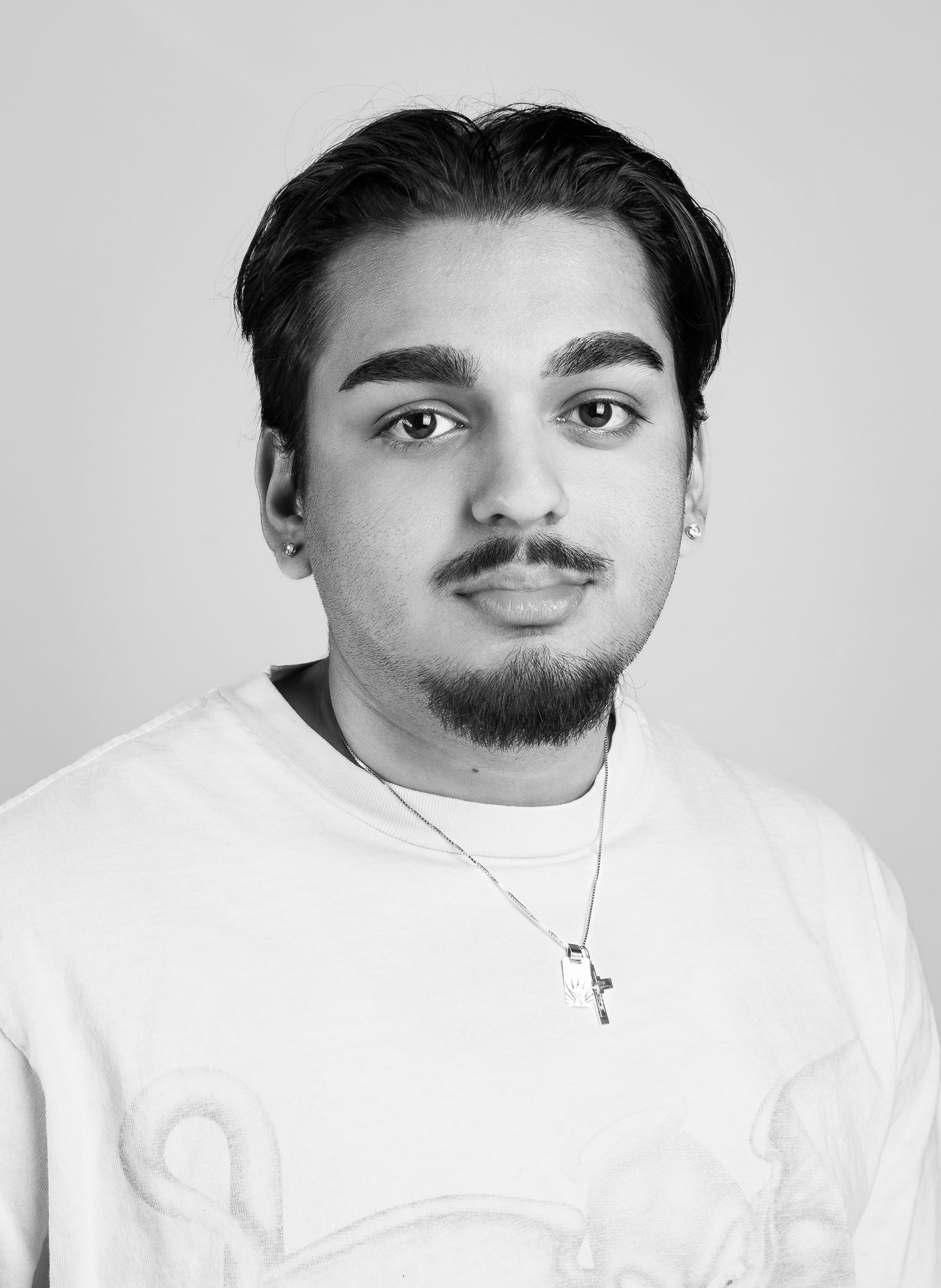 Black and white image of a boy in a white shirt with a neutral expression facing the camera