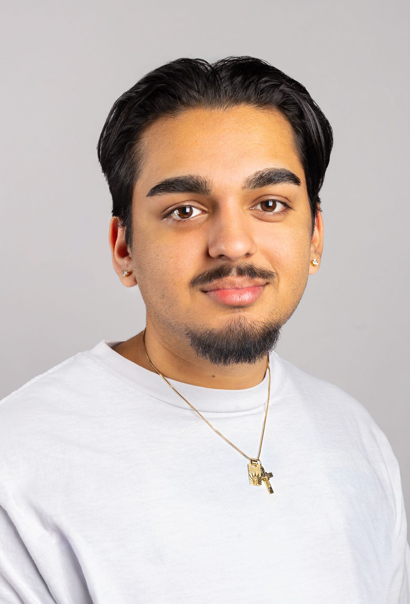 Image of a boy in a white shirt with a half smile, looking at the camera, side angle