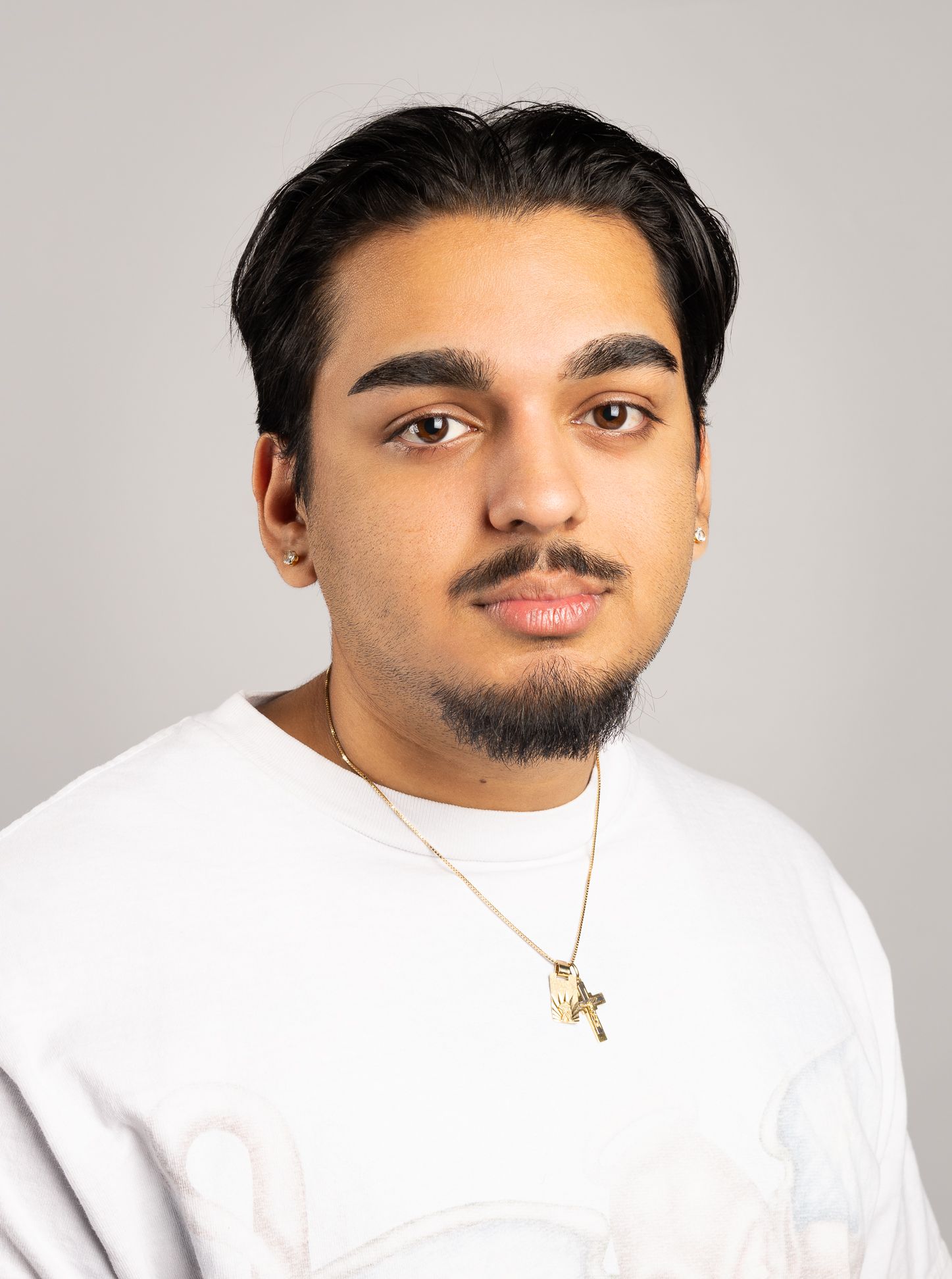 Image of a boy in a white shirt with a neutral expression looking at the camera, side angle