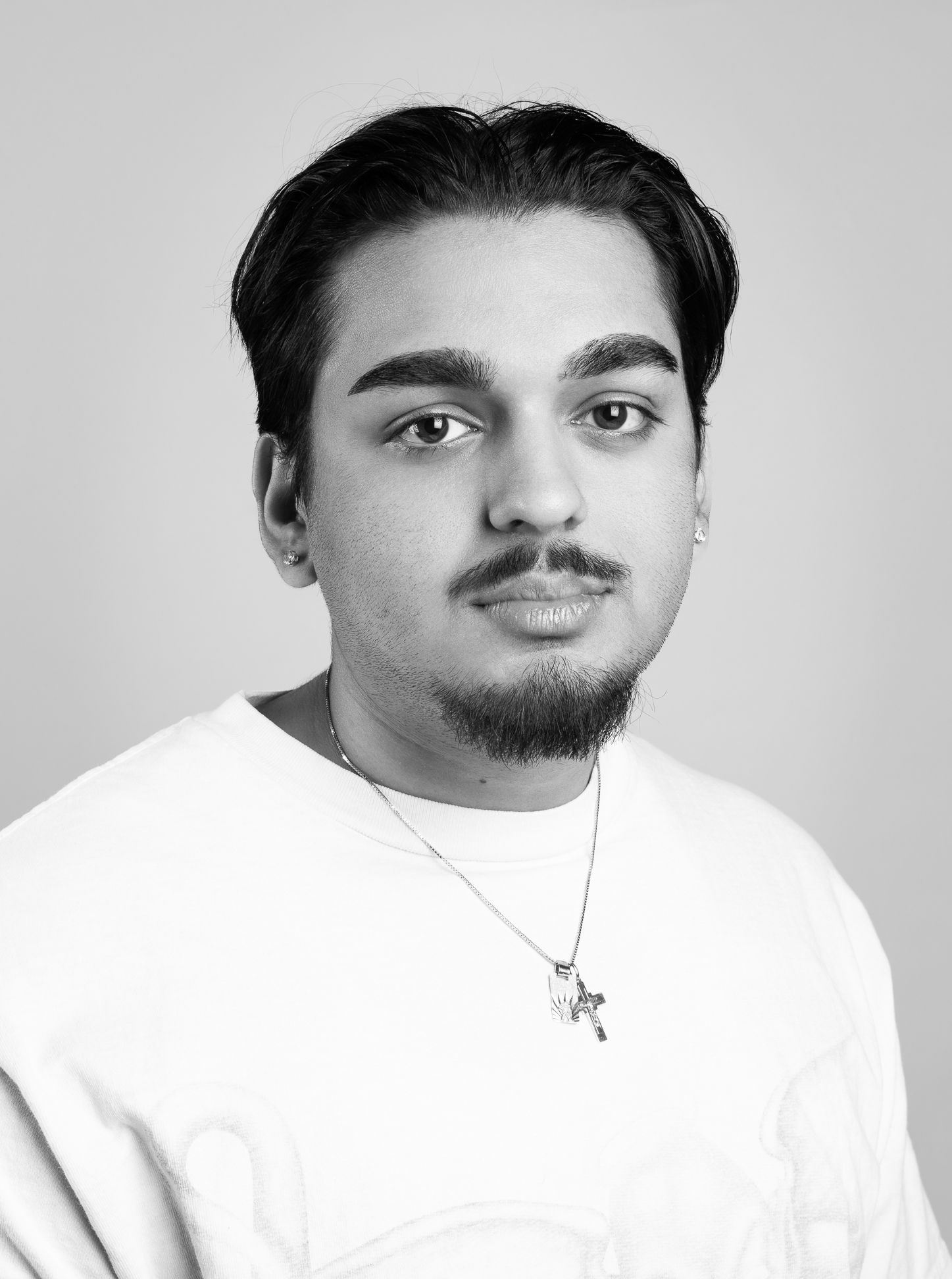 Black and white image of a boy in a white shirt with a neutral expression looking at the camera, side angle