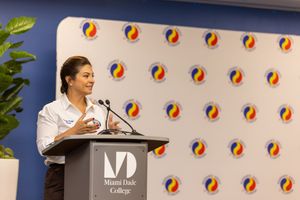 Speaker presenting at a technology conference with colorful circular logo patterns displayed on the backdrop wall.