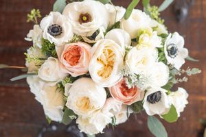 A lush bridal bouquet featuring pale pink and white garden roses with greenery.