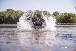 Person splashing through shallow water creating dramatic spray effect.