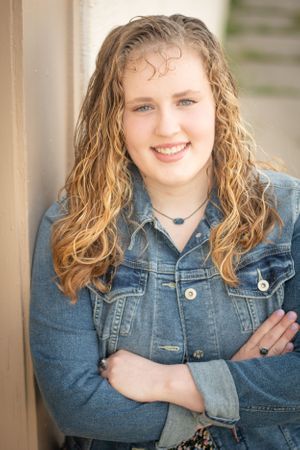 Portrait of someone with wavy blonde hair wearing a denim jacket.
