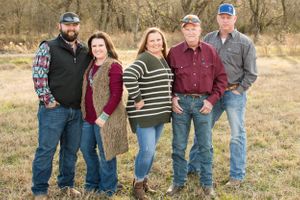Family group photo of five people standing together outdoors.