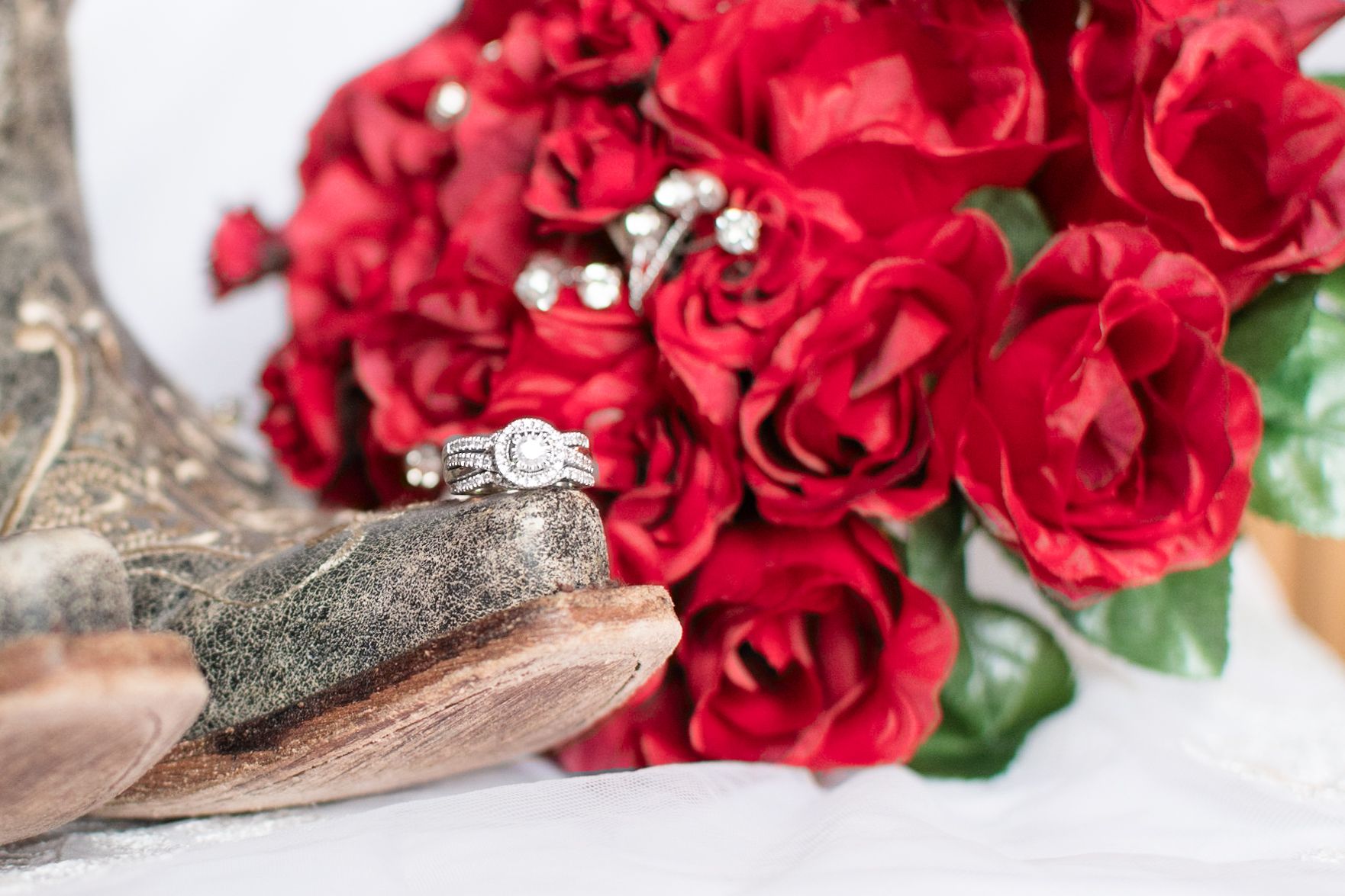 Diamond engagement ring with red roses on vintage background.