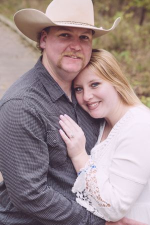 Couple in western attire posing for engagement photo outdoors.