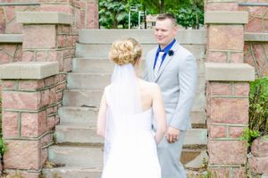 First look wedding moment on stone steps between couple in formal attire.