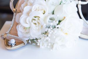 An elegant white floral bouquet and wedding ring displayed on a light surface.