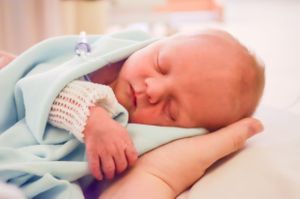 A peaceful sleeping newborn baby wrapped in a soft blue blanket.