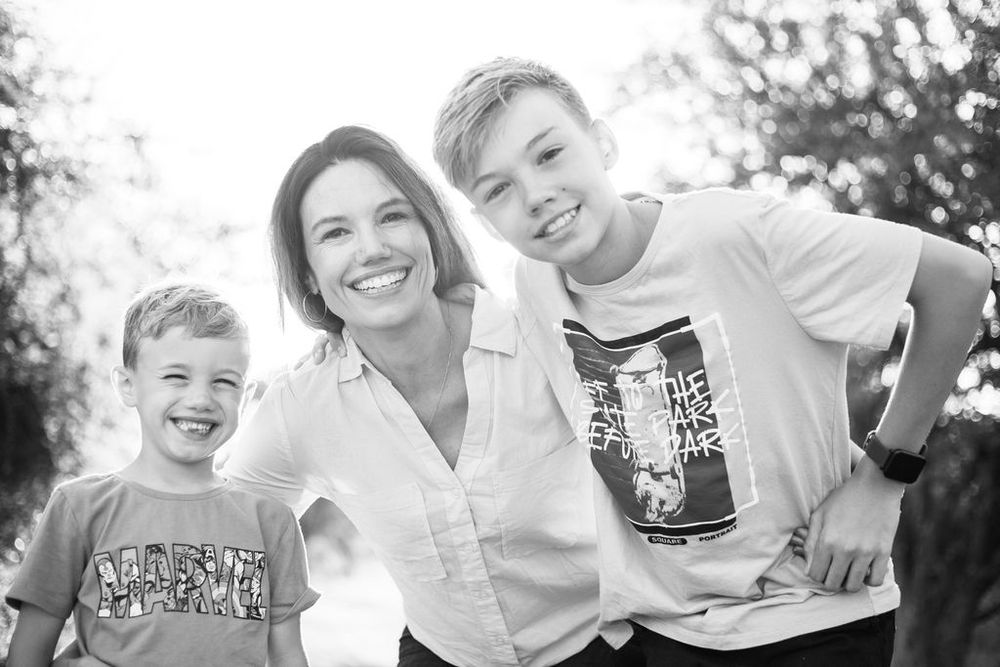 Black and white portrait of three smiling figures outdoors.