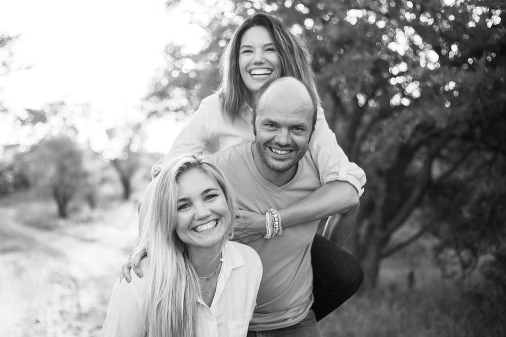 Candid black and white photo showing three people laughing together outdoors.