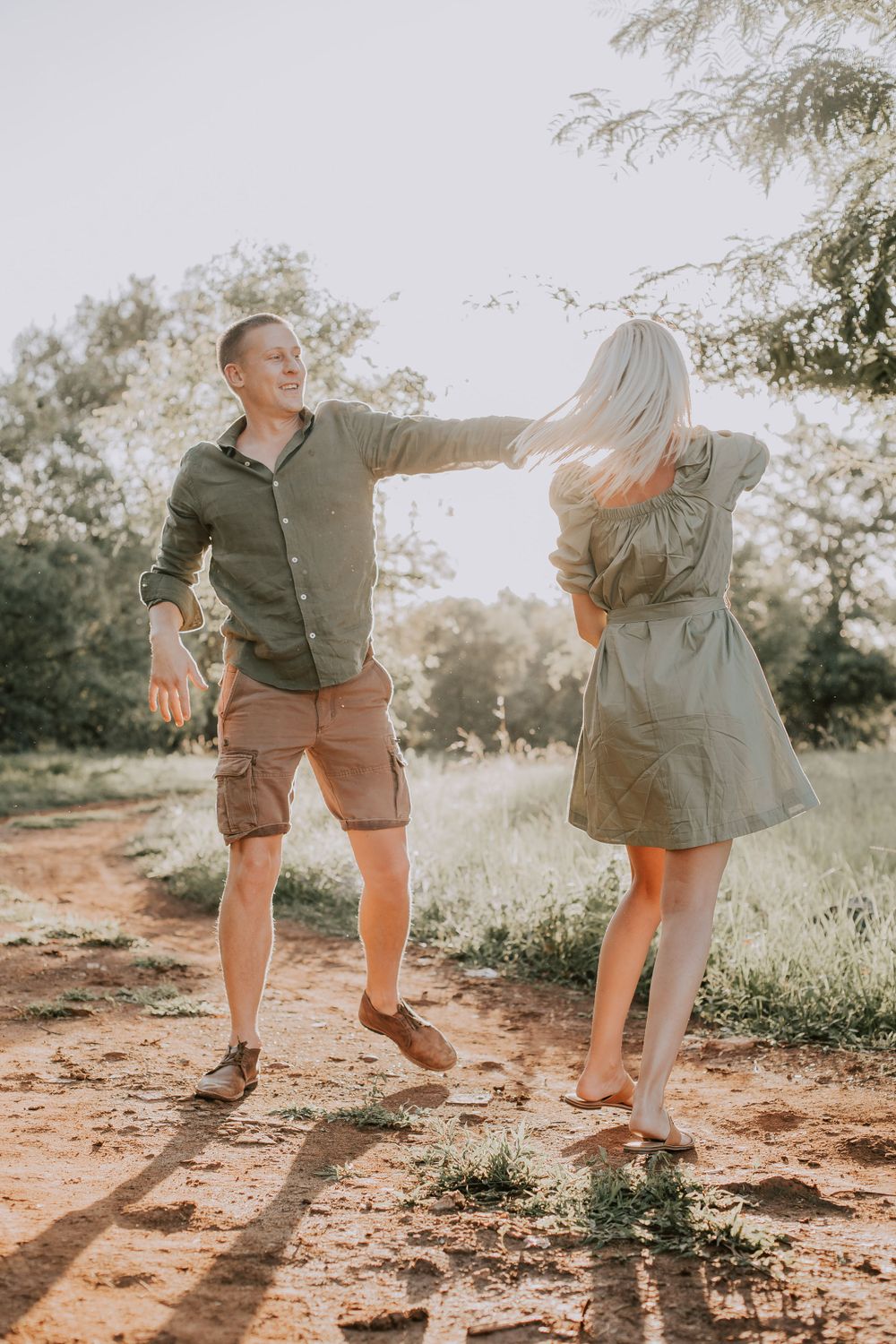 A playful couple having fun on a dirt path during golden hour.