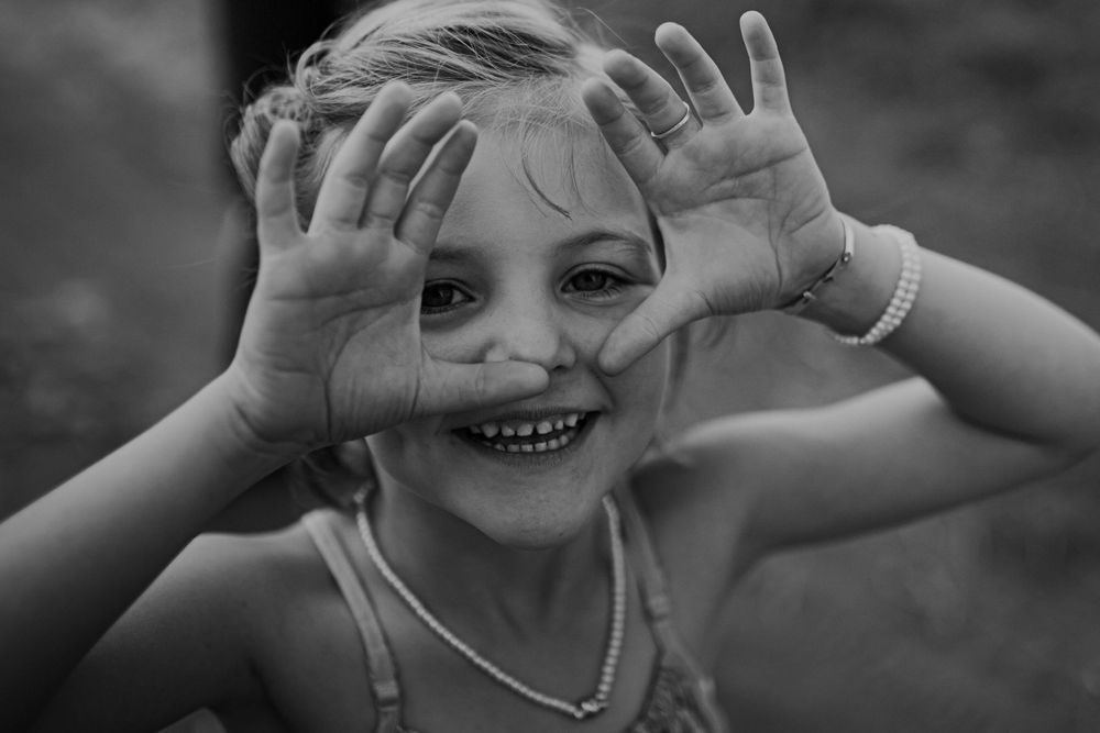 A joyful expression captured in black and white as hands frame a bright smile.