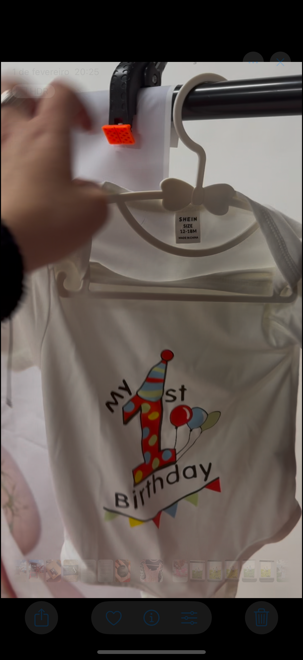 White birthday t-shirt with colorful balloon design on clothes hanger.