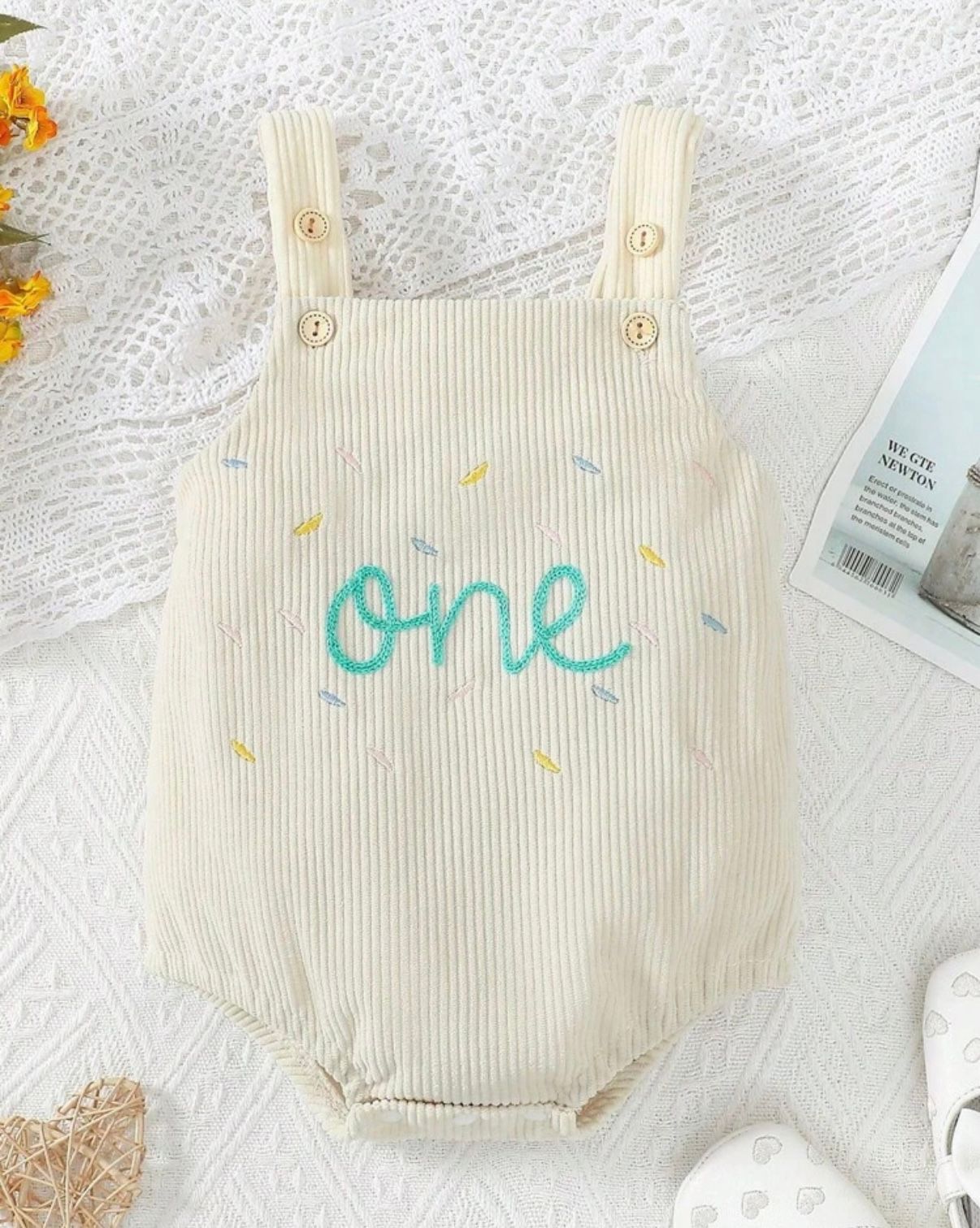 Cream colored ribbed baby romper with 'one' text embroidered on front.