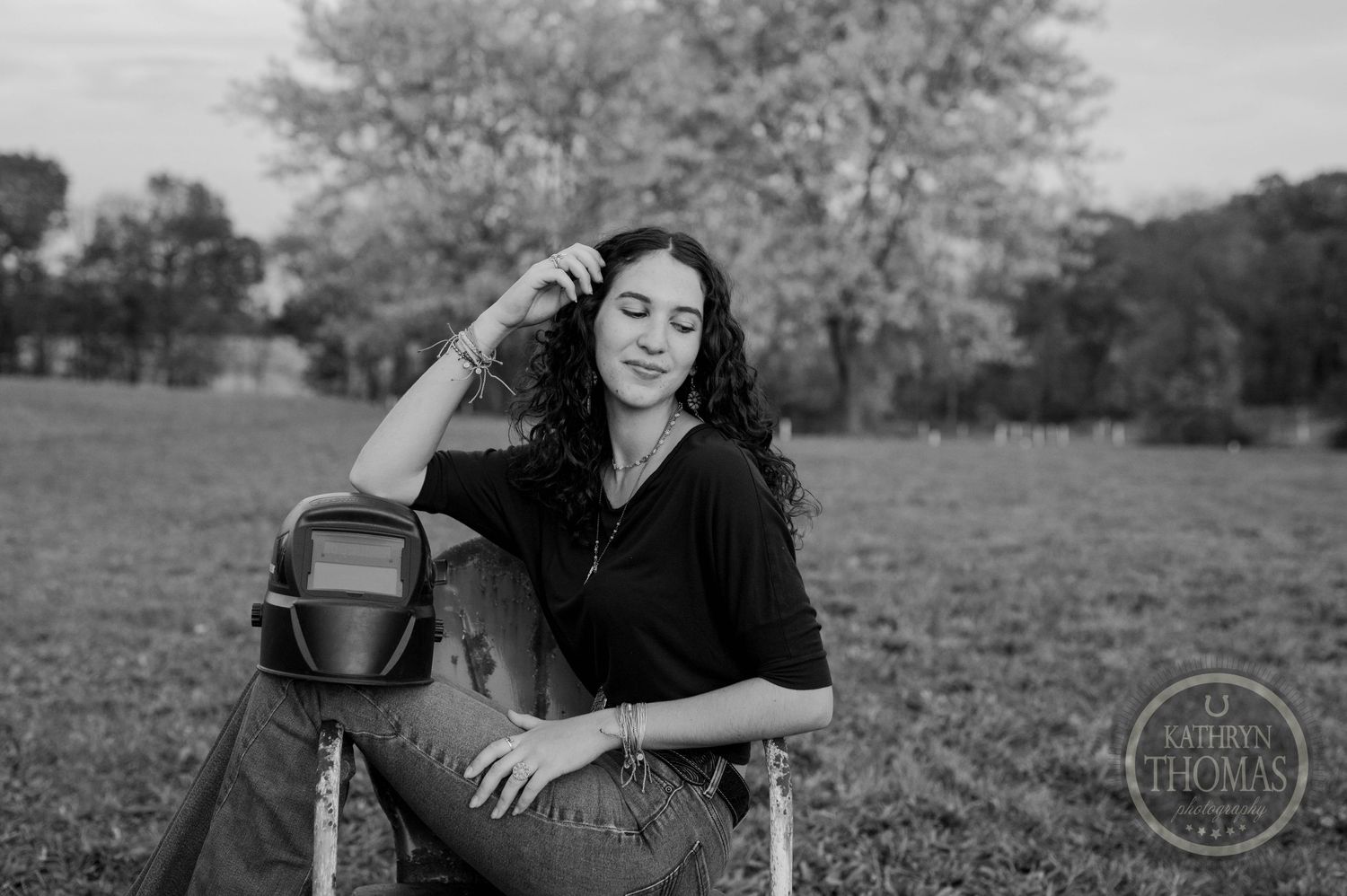 Black and white portrait of someone sitting in an outdoor field with camera gear.