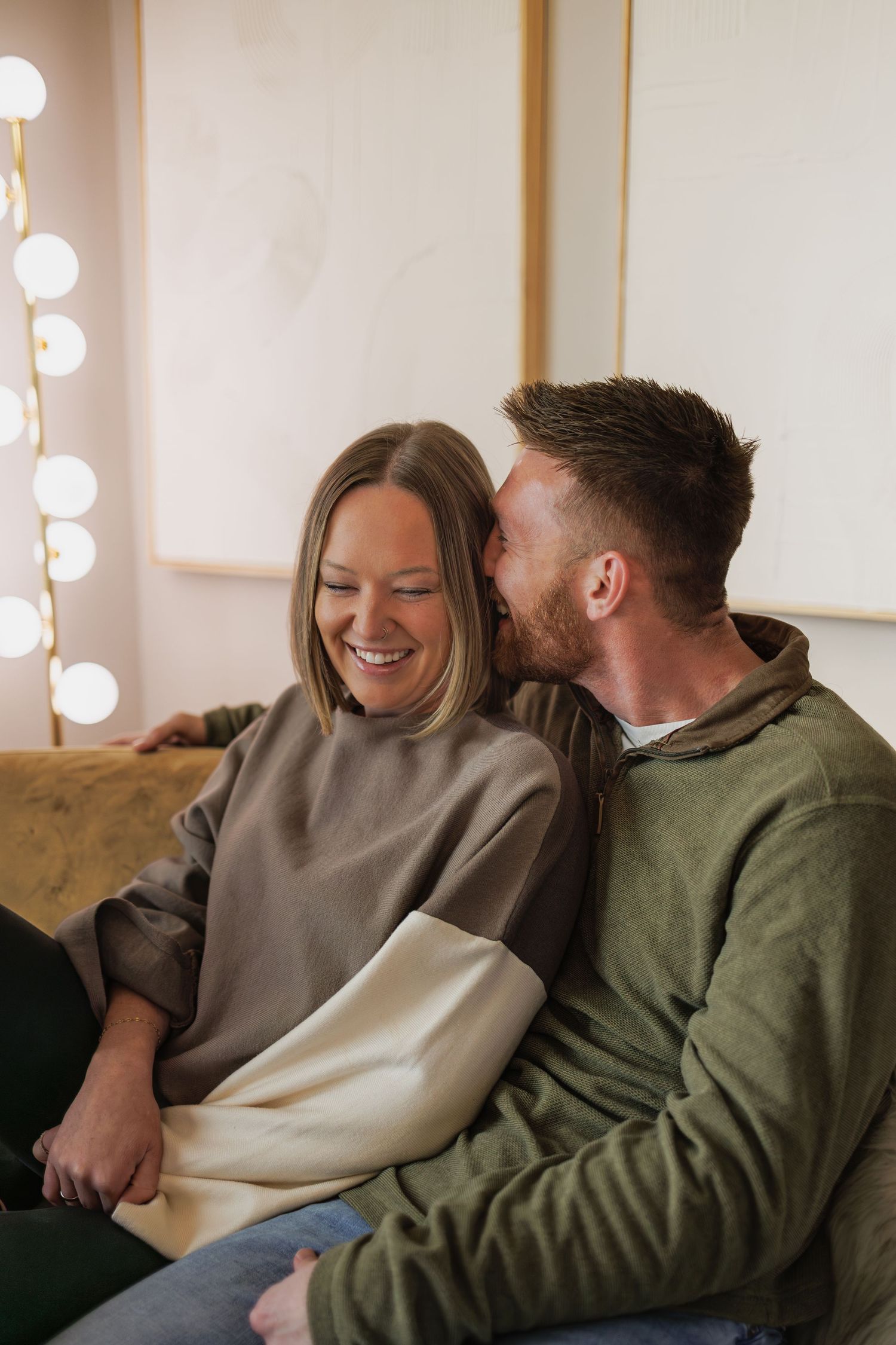 Couple laughing together on couch while sharing intimate moment.