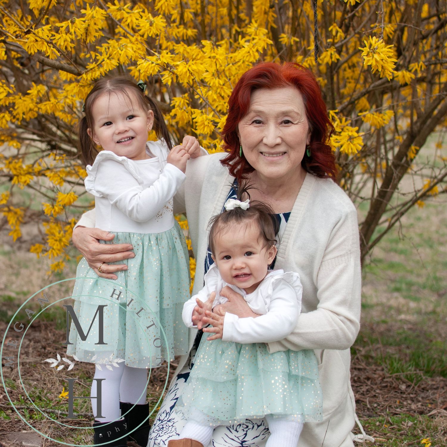 Image of a grandma and two little girls near a forsythia tree.
