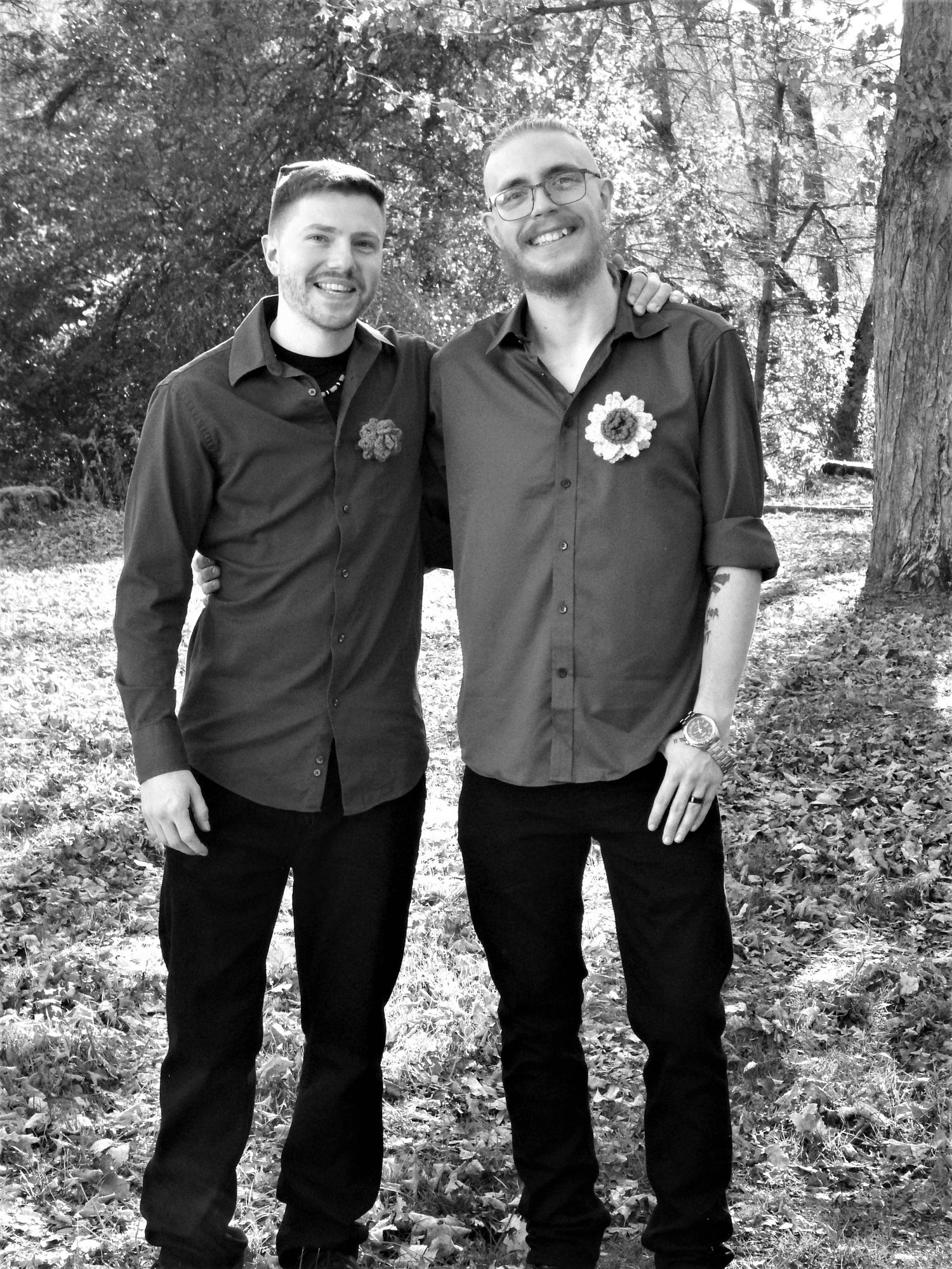 People pose together wearing coordinated black attire in an autumn forest setting.