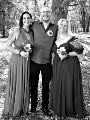 Wedding party poses in coordinated black and gray attire during an autumn outdoor photo session.