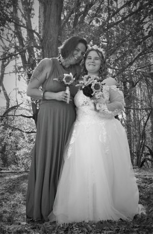 Outdoor wedding party photo with bridesmaids in gray and bride in flowing white dress.
