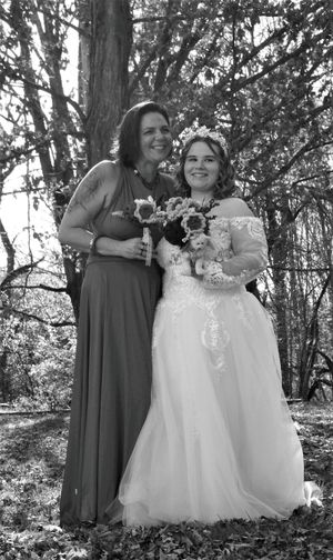 Candid wedding photo showing joyful moments between bridal party members in a forest setting.
