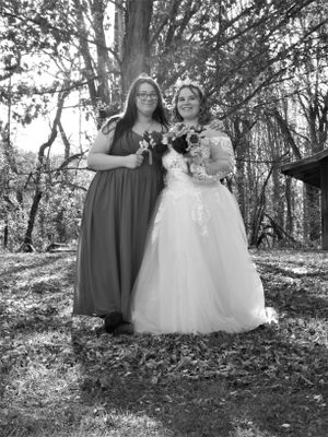 Casual outdoor wedding photo with bridal party members sharing laughs in wooded area.