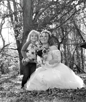A romantic outdoor photoshoot features two people in elegant dresses against a natural forest backdrop.