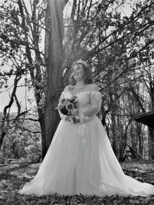 A magical forest scene features someone in a flowing white gown holding flowers among tall trees.