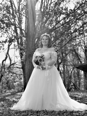 Black and white wedding portraits in a wooded setting showing a bride in an elegant ballgown dress with floral bouquet.