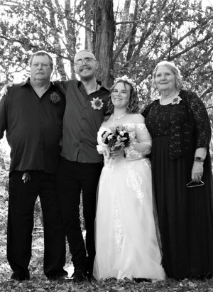 Wedding party group photo in black and white showing attendants dressed in dark attire alongside the bride.