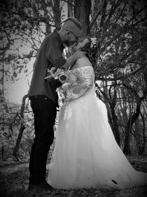 Wedding couple shares intimate moments in a wooded outdoor setting captured in black and white.