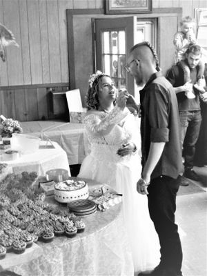 A newlywed couple shares a sweet moment while cutting their wedding cake together.