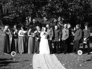 A formal wedding party photo taken outdoors with matching attire and natural backdrop.