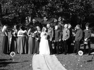 Wedding party poses on a path with trees in the background and coordinated formal wear.
