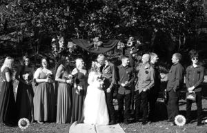 Bridal party stands in formation outdoors with bridesmaids and groomsmen flanking the couple.