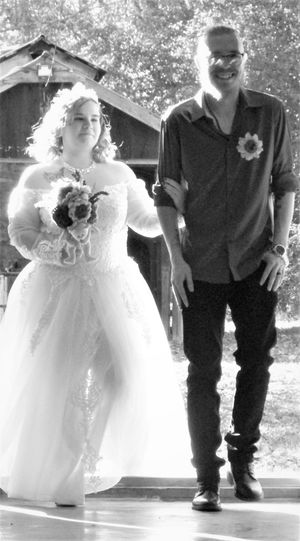 A small child in a white dress stands next to someone in black during a formal event.