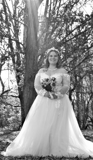 A bride in a strapless white gown poses for portraits in a forest setting.
