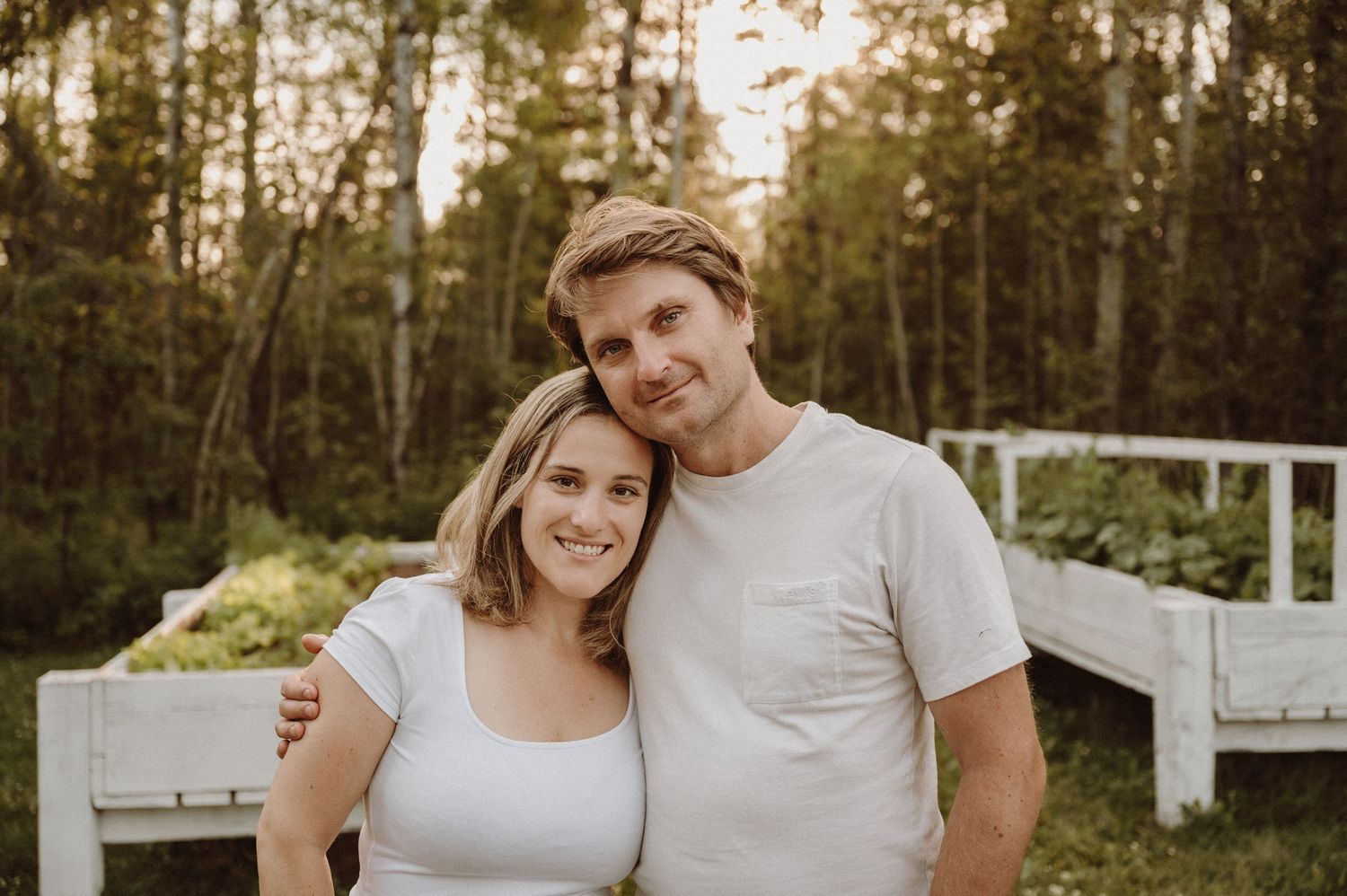 A couple smiling together on an outdoor deck with trees in background.