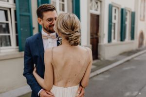 Brautpaar in einer Altstadtgasse von Heidelberg. Die Braut sieht man von hinten, sie hat einen tiefsitzenden Dutt und ein rückenfreies Kleid