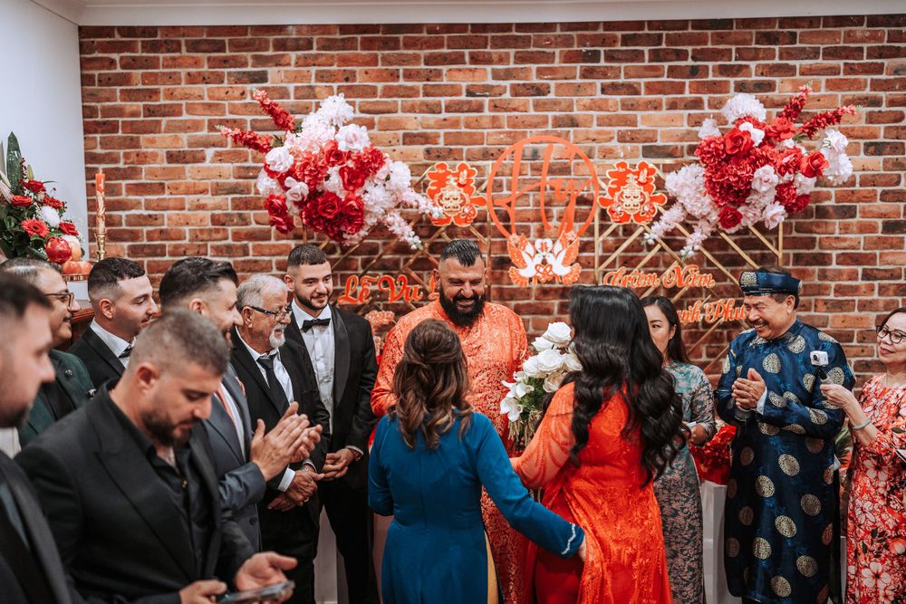 Festive wedding celebration with red and white balloons against brick wall backdrop during energetic party moment.