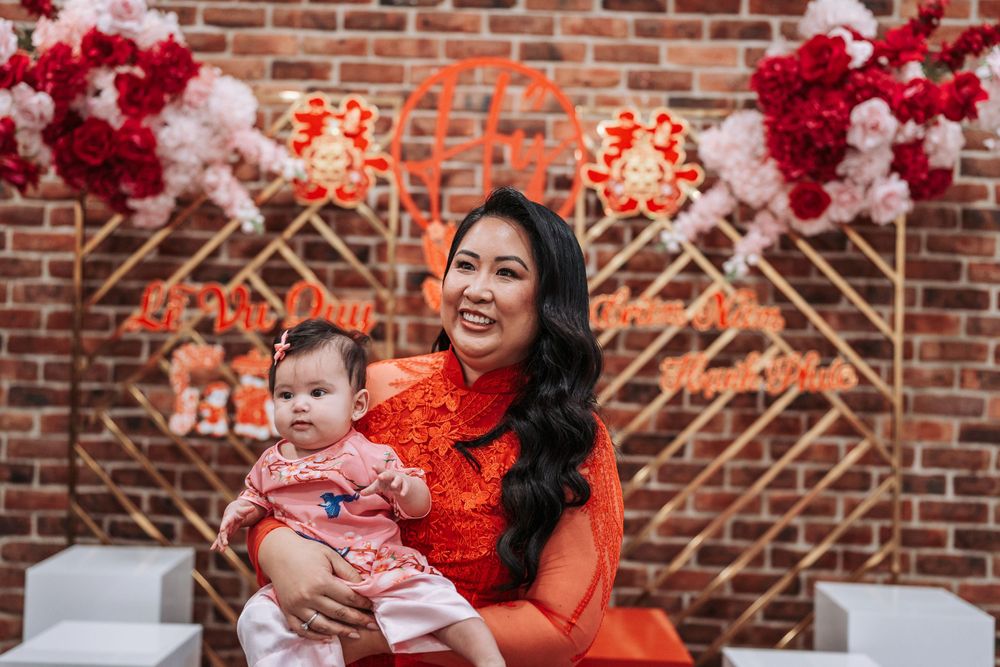 Traditional celebration with red and pink floral decorations against a brick wall backdrop.